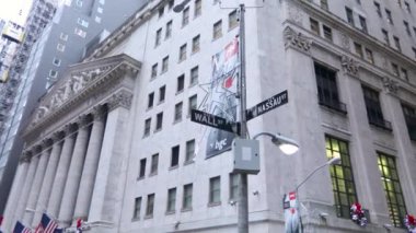 NEW YORK, ABD - 10 Aralık 2022: Amerikan bayrağı ve sokak tabelasıyla New York Borsa binasının yavaş çekim görüntüsü