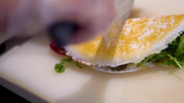 Yağsız biftek, mozzarella, taze domates, bebek roka ve fesleğen pesto sosuyla doldurulmuş parmesan kabuğuyla Tapioca ununun yavaş çekim görüntüsü.