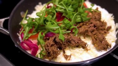Yağsız biftek, mozzarella, taze domates, bebek roka ve kızarmış tavada fesleğen sosu ile doldurulmuş parmesan kabuklu Tapioca unu pişirmenin yavaş çekim görüntüsü.