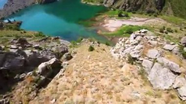 Güneşli bir günde Özbekistan 'da şişme botlarda yüzen turistlerin bulunduğu yeşim taşı Urungach Gölü' nün birinci şahıs görüntüsü