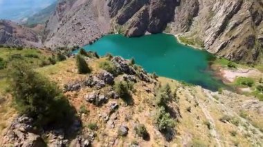 Güneşli bir günde Özbekistan 'da şişme botlarda yüzen turistlerin bulunduğu yeşim taşı Urungach Gölü' nün birinci şahıs görüntüsü