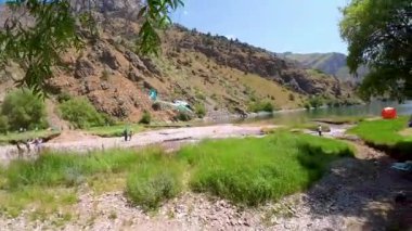 Taşkent, Özbekistan - 15 Mayıs 2024: Güneşli bir günde Özbekistan 'da kamp yapan turistlerle birlikte yeşim Urungach Gölü üzerinde uçan helikopterin birinci şahıs görüntüsü