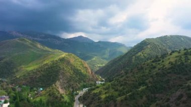 Yeşil tepeler ve bulutlu gökyüzü ile Özbekistan 'daki Zaamin Milli Parkı' ndan geçen bir dağ yolunun havadan görünüşü