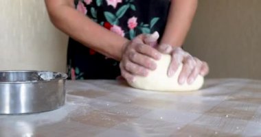 Masadaki hamuru yoğuran kadının yakın çekimi.