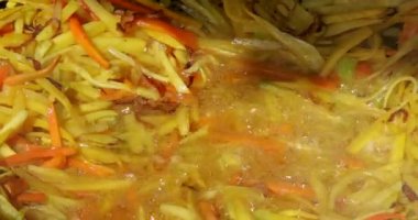 Closeup of frying sliced carrots in a cauldron
