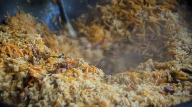 Tanınmayan adamın elleri pirinç palomuyla Kazan 'daki büyük spatulayı karıştırıyor.