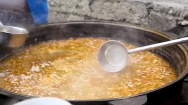 Özbek çorbasını büyük bir kazandan bardaklara dolduran kişi. Dünya mutfağı