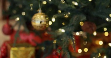 Yakından altın oyuncak topları bir Noel ağacına asılmış çelenkler ve hediyelerle. Noel ağacı süslemeleri.