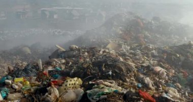 Arazi sahasında uçan kargalarla dolu çöp yığınlarının yakılması