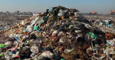 Çöp sahasında çöp yığınlarının yakılması ve arka planda çöp ve çöp kamyonlarının geri dönüşümü