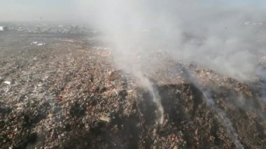 Arazinin üzerinde uçan kargalarla yanan çöp yığınlarının hava görüntüsü