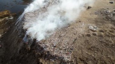 Yanan çöp yığınlarıyla dolu hava manzarası ve kirlenmiş zehirli gölet