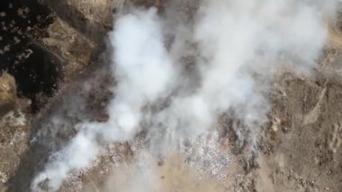 Yanan çöp yığınlarıyla dolu hava manzarası ve kirlenmiş zehirli gölet