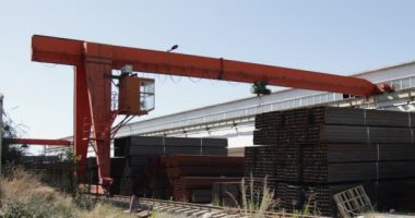 Gantry vinci çelik fabrikasında metal borular taşıyor.