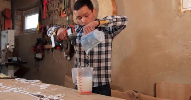 Marangoz epoksi reçineyi elektrikli mikserle karıştırıyor. El yapımı reçine ve ahşap masa.