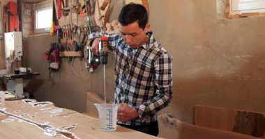 Marangoz epoksi reçineyi elektrikli mikserle karıştırıyor. El yapımı reçine ve ahşap masa.