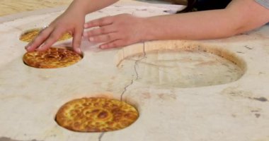 Person placing flatbreads into wooden round epoxy table. Creative epoxy table design