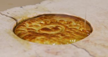 Marangoz, ahşap yuvarlak bir epoksi masasına yassı ekmeklerle süslenmiş sıvı epoksi döküyor. Yaratıcı epoksi tablo tasarımı