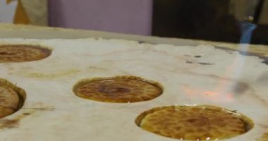 Marangoz hava kabarcıklarını, tahta, yuvarlak, epoksi masasından flatekslerle süslenmiş pürmüzle temizliyor. El yapımı reçine ve ahşap masa.