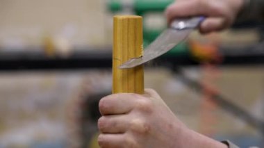 Closeup of carpenter cutting table leg with hand saw