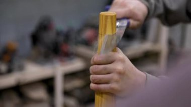 Closeup of carpenter cutting table leg with hand saw