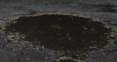 Closeup of dripping raindrops in a puddle in rainy day