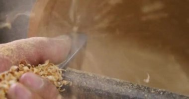 Marangozun torna tezgahına odun çevirdiği yakın plan. Torna tezgahına keski şamdanı oyan kişi