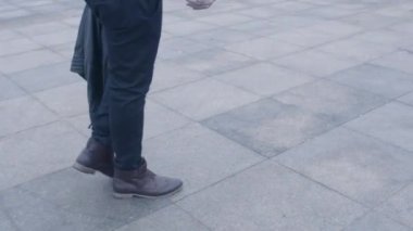 Ağır çekimde yürüyen adamın deri kahverengi ayakkabıları.