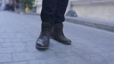 Ağır çekimde yürüyen adamın deri kahverengi ayakkabıları.