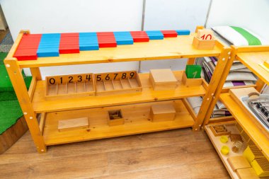 Renkli sayma çubukları, tahta blokları ve çeşitli eğitim araçlarıyla Montessori matematik öğrenme rafı