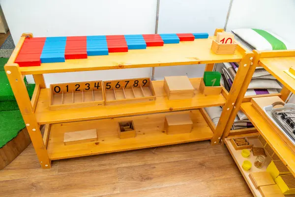 Renkli sayma çubukları, tahta blokları ve çeşitli eğitim araçlarıyla Montessori matematik öğrenme rafı