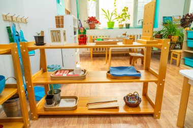 Wooden Montessori classroom setup featuring shelves with organized educational materials like cups, bowls, and tools for child development activities clipart