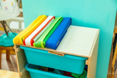 Stacked colorful mats neatly arranged on a Montessori classroom shelf, promoting organization and hands-on learning in early childhood education clipart