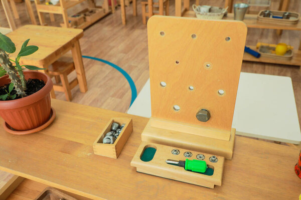 Close-up of Montessori tool featuring screws, bolts, and a screwdriver, promoting fine motor skills and practical life activities in children
