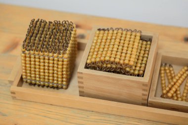 Montessori matematik küpü ve hacim ve kareler gibi matematiksel kavramları öğretmek için kare materyallerin ahşap bir rafa yerleştirilmiş yakın çekimi.