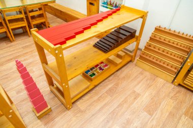 Montessori Pembe Kulesi 'ni diğer eğitim bloklarının yanında gösteren ahşap bir raf.