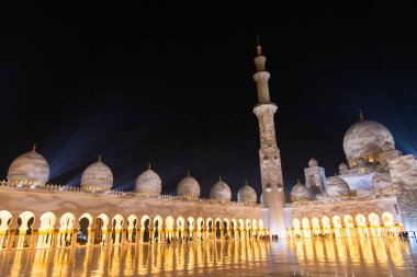 Abu Dabi, BAE - 23 Nisan 2024: Şeyh Zayed Büyük Cami 'nin kubbeleri ve kemerleri gece parlayan mermer zemine yansıdı