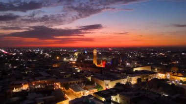 Özbekistan 'ın Bukhara şehrinde günbatımında Kalan Camii ve Buhara Sandığı' nın hava manzarası dramatik bir gökyüzü altında aydınlatılmış şehir ışıklarıyla