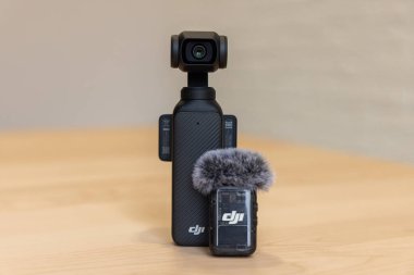 Bishkek, Kırgızistan - 4 Kasım 2024: DJI Osmo Pocket 3 kameranın ön görüntüsü DJI Mic 2 Vericisi ile ahşap masa üzerinde ön cam