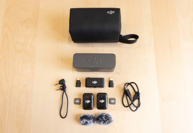 Bishkek, Kırgızistan - 4 Kasım 2024: DJI MIC 2 mikrofon kiti içinde vericiler, alıcı, şarj çantası, ses kabloları, adaptörler, ön ekranlar ve ahşap yüzeye yerleştirilmiş çanta