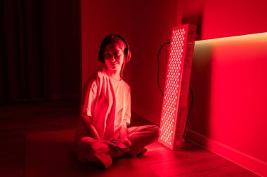 Kırmızı ışık terapi seansı sırasında yaşlı bir kadının el ve kolunun yakın çekimi.