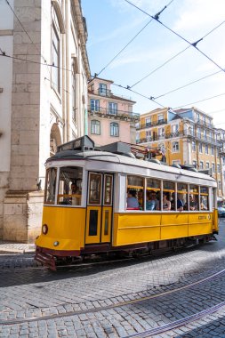 Lizbon, Portekiz - 12 Mayıs 2024: Dolu bir sarı tramvay eski şehir merkezinde dönüş yapıyor