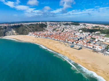 Sahile yaklaşan kıyı dalgası tepedeki Nazare kasabasını gösteriyor.