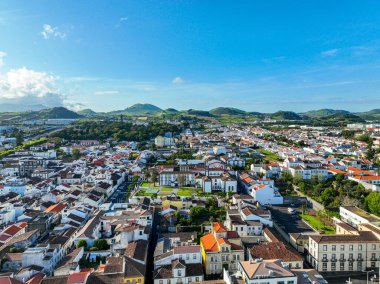 Arka planında kırmızı çatıları, yeşilliği ve manzaralı tepeleri olan Ponta Delgada 'nın yerleşim bölgesi.