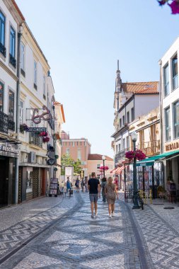 Aveiro, Portekiz - 12 Mayıs 2024: Aveiro 'nun eski kasabasında bulunan ve çeşitli etnik köken ve çağlardan gelen geleneksel binalar, dükkanlar ve insanların kendine özgü kaldırım taşları üzerinde yürüdüğü pitoresk bir yaya sokağı