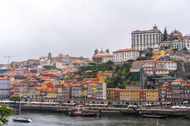 Porto, Portekiz - 12 Mayıs 2024: Porto 'nun canlı nehir kenarı bölgesinin geniş panoramik manzarası, tepelerden Douro Nehri' ne doğru çağlayan renkli geleneksel evler ve ufuk çizgisinin üzerindeki tarihi binalar