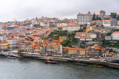 Porto, Portekiz - 12 Mayıs 2024: Porto 'nun tarihi şehir manzarası, Douro Nehri kıyıları boyunca uzanan yoğun renkli binalar ve terracotta çatıları, parlak bir gökyüzü altında