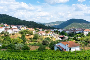 Beyaz evleri ve kırmızı çatıları olan büyüleyici bir köy yeşil bir vadiye kurulmuş. Parlak bir gökyüzünün altında yemyeşil tepelerle çevrili.