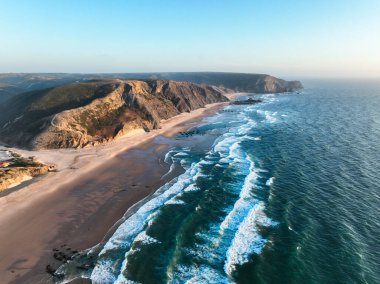 Portekiz 'deki Praia da Cordoama' da kayalık sahil şeridine çarpan dalgaların çarpıcı görüntüsü.