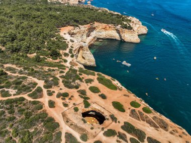 Okyanus yakınındaki Benagil Mağarası 'nda turistler ve kanolar görünüyor.